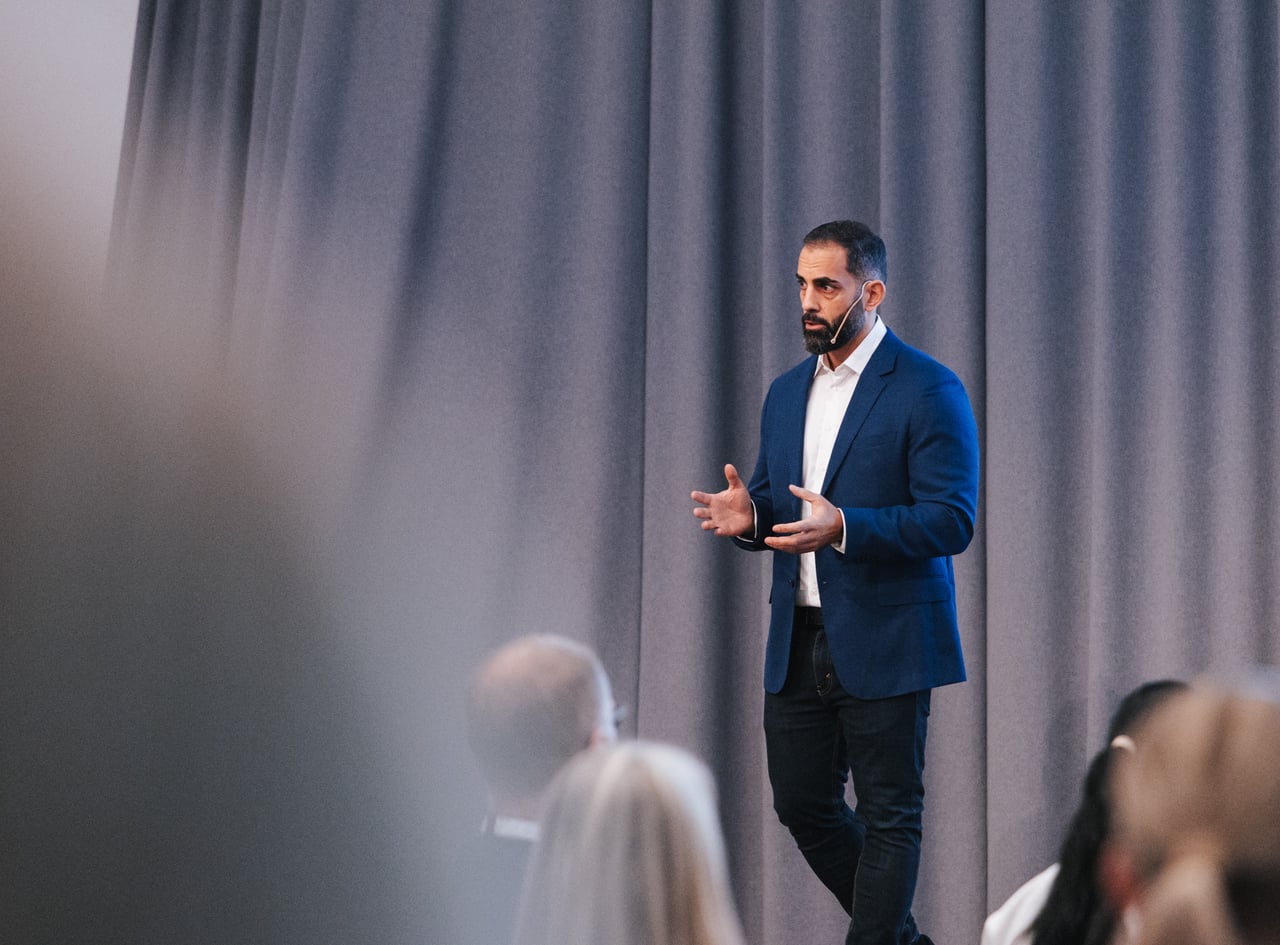 Sam Sorodi holder foredrag på scene for et engasjert publikum